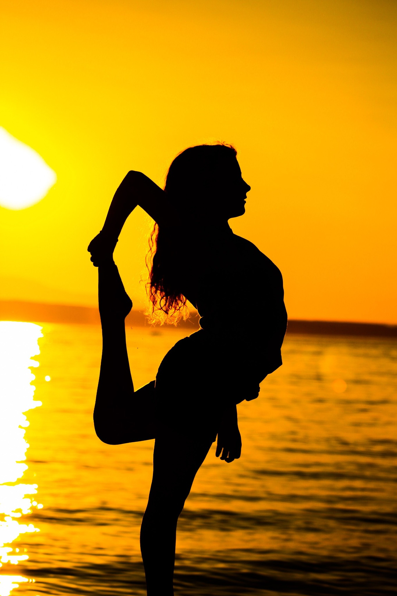 A person practising yoga at sunset